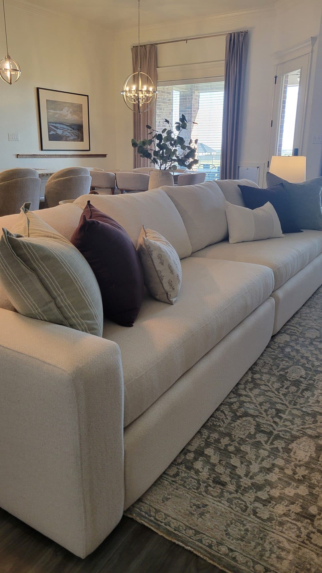 Deep cream sectional layered with plum, sage, and navy pillows